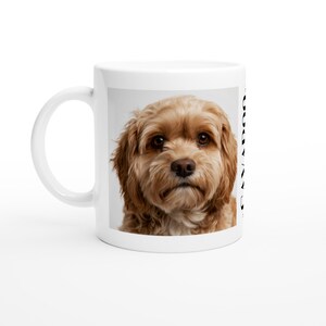 Può includere: Una tazza in ceramica bianca con una stampa fotografica ad alta risoluzione di un cane dal pelo marrone chiaro e soffice con grandi occhi scuri. Il lato della tazza mostra il testo verticale nero CAVAPOO accanto al ritratto del cane.