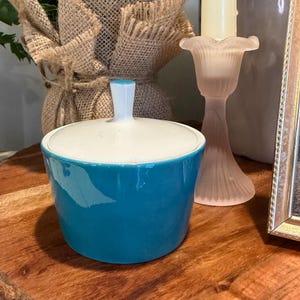 Peut inclure: Un sucrier en céramique turquoise avec un couvercle et une poignée blancs. Le bol est cylindrique avec une finition brillante. Le couvercle est rond et s'adapte parfaitement. Un article décoratif pour la cuisine ou la salle à manger.