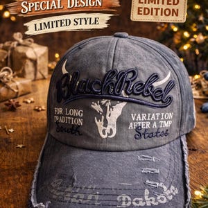 Könnte beinhalten: Verwaschene graue Baseballkappe mit dem gestickten Schriftzug "BlackRebel" auf der Vorderseite. Mit einem Bullen-Motiv und Text wie "Dakota" und "Limited Edition". Die Kappe hat einen Used-Look.