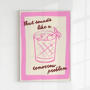 Op de afbeelding: Ingelijste kunstdruk met een roze rand en een crèmekleurige achtergrond. De print toont een roze illustratie van een cocktail met ijs en kersen, en de tekst "That sounds like a tomorrow problem" in bordeaux.