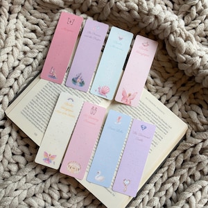 May include: Eight rectangular bookmarks with pastel colours and various illustrations including butterflies, castles, fairies, and ballet slippers. Each bookmark features printed text titles such as Mariposa, The Princess and the Pauper, Barbie Mermaidia, Barbie Fairytopia, Magic of the Rainbow, 12 Dancing Princesses, Swan Lake, and The Diamond Castle.