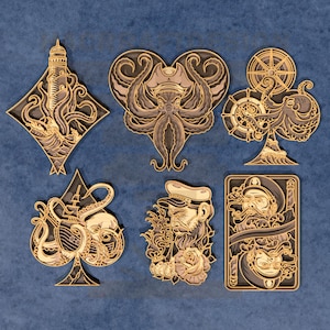 Puede incluir: Colección de obras de arte de madera en capas con diseños náuticos y de criaturas marinas. Las piezas incluyen un faro, un pulpo en forma de corazón, un timón, una pica con un barco y un pulpo, un marinero con una rosa y una carta de juego.