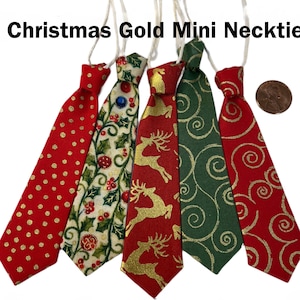 May include: A collection of five mini Christmas neckties in various festive designs. The ties feature patterns like gold polka dots, holly, reindeer, and swirls, with red and green backgrounds. Each tie is attached to a white string for hanging. The text "Christmas Gold Mini Necktie" is at the top.