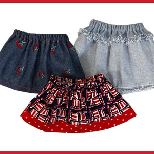 May include: Three denim skirts, one with a cherry embroidery, one with a frayed hem, and one with a red, white, and blue print.