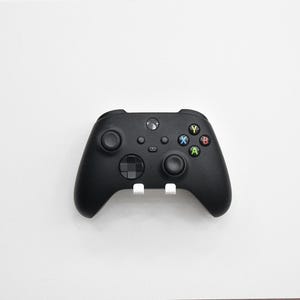 Könnte beinhalten: Ein mattschwarzer kabelloser Videospiel-Controller mit zwei Analogsticks, einem Steuerkreuz und vier Aktionstasten, die mit den Buchstaben A, B, X und Y in den Farben Grün, Rot, Blau beziehungsweise Gelb beschriftet sind.