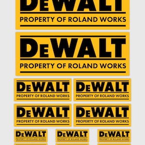 Op de afbeelding: Een verzameling gele en zwarte rechthoekige stickers. Het woord "DEWALT" staat prominent in vette zwarte letters. Daaronder staat de tekst "PROPERTY OF ROLAND WORKS" afgedrukt. Verschillende formaten worden getoond.