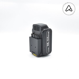 May include: A black and grey 18V 5.0Ah Li-ion battery pack for power tools. The battery has a rectangular shape with a black housing and a label with white text. Designed for use with power tools.