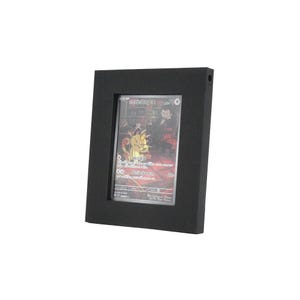 Op de afbeelding: Een zwart, rechthoekig frame omsluit een ruilkaart. De kaart heeft een kleurrijke illustratie met Japanse tekst. Het frame heeft een klein gaatje rechtsboven.