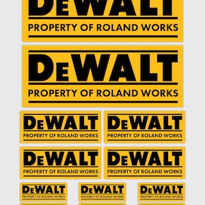 Op de afbeelding: Een verzameling gele en zwarte rechthoekige stickers met het "DEWALT" logo en de tekst "PROPERTY OF ROLAND WORKS". De stickers variëren in grootte, met de grootste bovenaan en kleinere eronder.