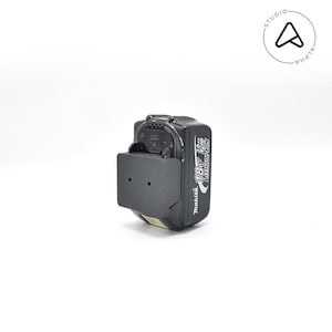 May include: A black Makita 18V 3.0Ah Lithium-Ion battery pack with a black mounting bracket. The battery pack has white text and a black and white logo. The image is set against a white background.