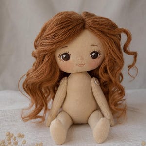 May include: A handmade fabric doll with light beige skin and long, wavy auburn yarn hair. The doll features embroidered facial details, including dark brown eyes with long lashes and a small mouth. The arms are attached with visible round buttons.