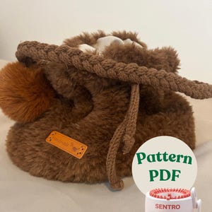 May include: A brown, plush drawstring bag with a braided rope handle and a fluffy pom-pom. A small, rectangular tag reads "Handmade". A white circle with green text says "Pattern PDF" next to a small knitting machine.