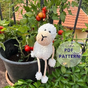 May include: A handmade white and beige sheep plush toy with a round head, long legs, and pom-pom feet. The sheep is set against a backdrop of a tomato plant with red tomatoes and green leaves. The image includes the text "PDF PATTERN".