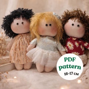 May include: Three handmade fabric dolls with different hairstyles and outfits. The dolls have rosy cheeks and button eyes. The doll on the left wears a sequined dress, the middle doll has a tutu, and the right doll has a floral top. The dolls are approximately 6.3 to 6.7 inches tall.