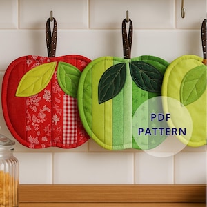 Könnte beinhalten: Drei apfelförmige, gesteppte Topflappen in Rot, Grün und Gelb, die an einer Metallstange hängen. Der rote Topflappen hat ein Blumen- und Vichy-Muster, während die grünen und gelben gestreifte Designs haben. Jeder hat eine braune Schlaufe zum Aufhängen und grüne Blattakzente. Der Text "PDF PATTERN" ist sichtbar.
