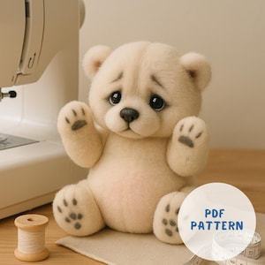 May include: A cream-colored teddy bear with black eyes and paw pads, sitting with its arms raised. A wooden spool of thread, a measuring tape, and a sewing machine are in the background. The image includes the text "PDF PATTERN".