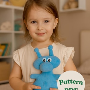 Può includere: Un giocattolo di peluche blu chiaro a forma di alieno con grandi occhi mobili e due antenne. Il giocattolo è tenuto in mano da un bambino. Un grafico circolare con il testo "Pattern PDF" è nell'angolo in basso a destra.