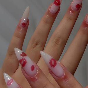 Peut inclure: Longs ongles en acrylique pointus avec une finition brillante. Les ongles sont peints avec un d&eacute;grad&eacute; de rose et de blanc, et pr&eacute;sentent des motifs de l&egrave;vres rouges. Le motif est r&eacute;p&eacute;t&eacute; sur chaque ongle, cr&eacute;ant un look coh&eacute;rent et &eacute;l&eacute;gant.
