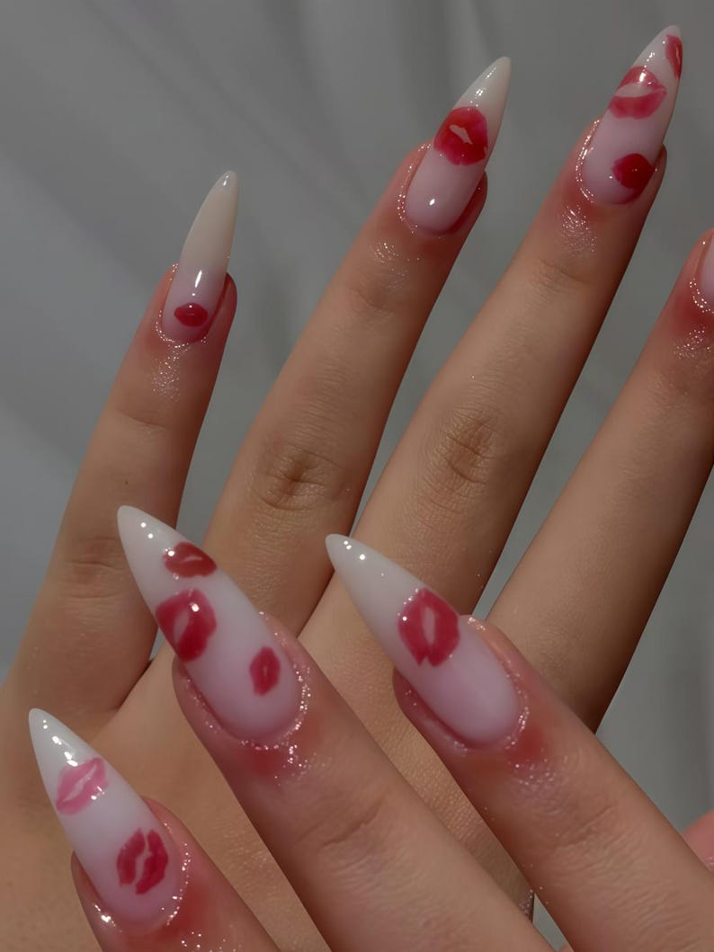 Peut inclure: Longs ongles en acrylique pointus avec une finition brillante. Les ongles sont peints avec un d&eacute;grad&eacute; de rose et de blanc, et pr&eacute;sentent des motifs de l&egrave;vres rouges. Le motif est r&eacute;p&eacute;t&eacute; sur chaque ongle, cr&eacute;ant un look coh&eacute;rent et &eacute;l&eacute;gant.