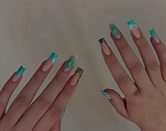 May include: A set of long, square acrylic nails. The nails feature a variety of designs, including a teal and white marble effect, gold accents, and a nude base with a white French tip. Some nails have gold embellishments.