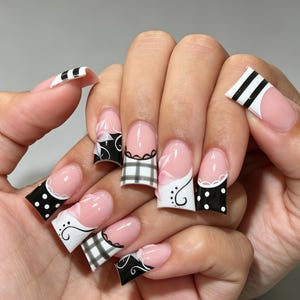 May include: Square-shaped artificial nails featuring a French manicure base with a nude pink tone. The tips are decorated with black and white patterns including polka dots, plaid, and swirling lines, accented by delicate white scalloped edges.