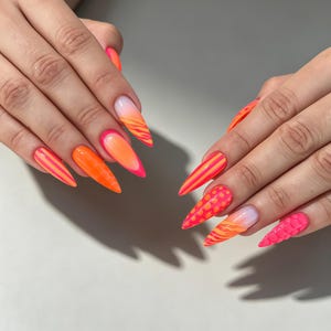 Puede incluir: Uñas largas en forma de estilete con una vibrante paleta de colores neón. Los diseños incluyen rayas verticales de color naranja brillante y rosa, naranja neón sólido, lunares y texturas inspiradas en patrones de animales.