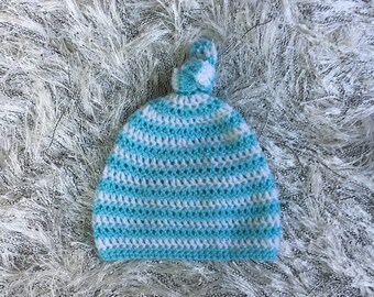 May include: A blue and white striped crocheted baby hat with a white pom-pom on top.