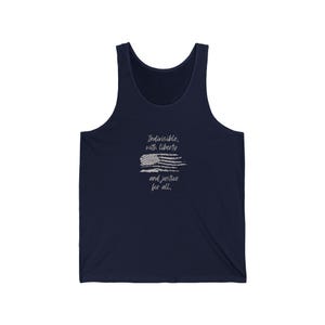 May include: Navy blue tank top with a white graphic of an American flag and the text "Indivisible, with liberty and justice for all." The sleeveless shirt is made of a soft material.