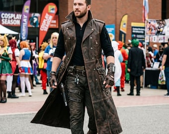 May include: A long, distressed brown leather duster coat worn over a black long-sleeve shirt and dark trousers. The outfit includes a brown leather belt with a holster, fingerless leather gloves, and brown boots, creating a rugged, layered look.