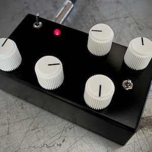 May include: Black box with five white knobs and two toggle switches. The box has a red LED light on the top.