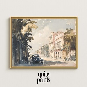 May include: A framed vintage print of a street scene with a classic car, palm trees, and buildings. The artwork is in muted tones of beige, brown, and gray, with a gold frame. The text "quite prints" is at the bottom.
