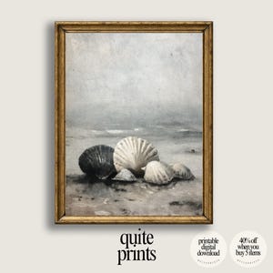Può includere: Una stampa incorniciata con una scena costiera con conchiglie. L'opera raffigura diverse conchiglie nei toni del bianco e del grigio su una spiaggia sabbiosa, con uno sfondo morbido e attenuato dell'oceano e del cielo. La cornice è dorata.