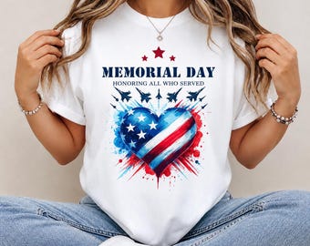 May include: White t-shirt featuring a patriotic heart design in red, white, and blue, with stars and jets. The text reads "MEMORIAL DAY HONORING ALL WHO SERVED". A casual tee for celebrating Memorial Day.