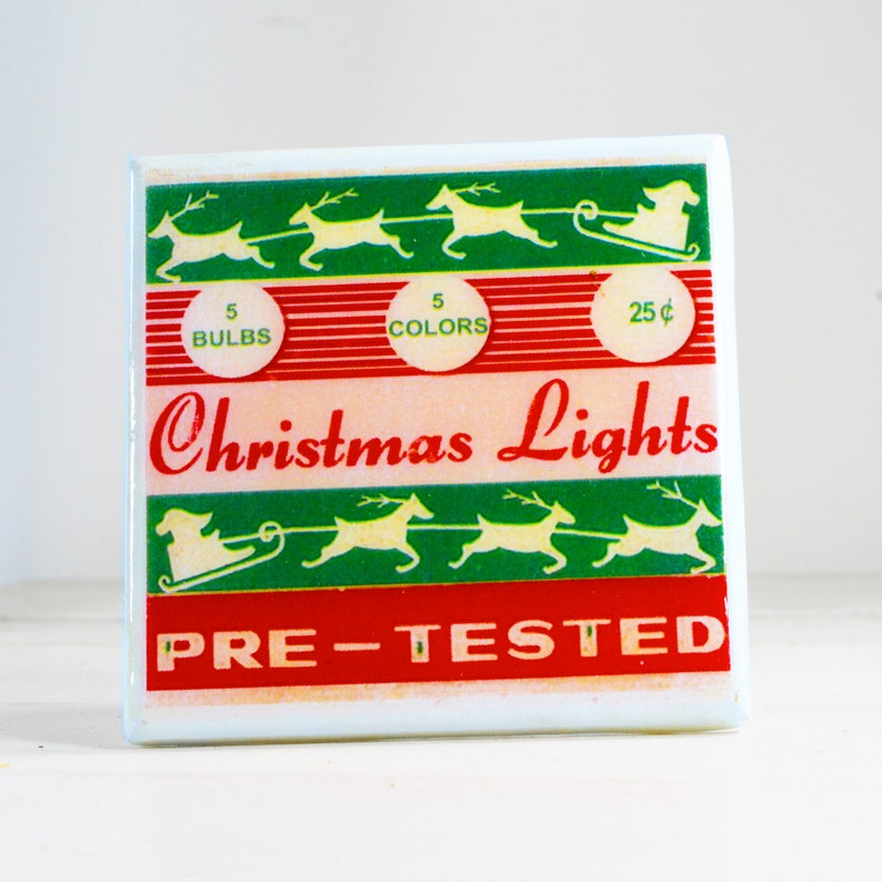 May include: Vintage Christmas light box with a red and green striped design. It features a white silhouette of a reindeer pulling a sleigh with Santa Claus. The box says "Christmas Lights" and "Pre-Tested" in red letters. It also says "5 Bulbs", "5 Colors", and "25 cents".