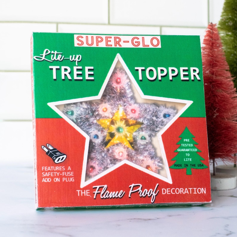 May include: A vintage Christmas tree topper in a star shape, encased in a box with green, red, and white accents. The box reads "SUPER-GLO Lite-up TREE TOPPER" and "THE Flame Proof DECORATION". The star has a silver tinsel appearance with colorful lights.