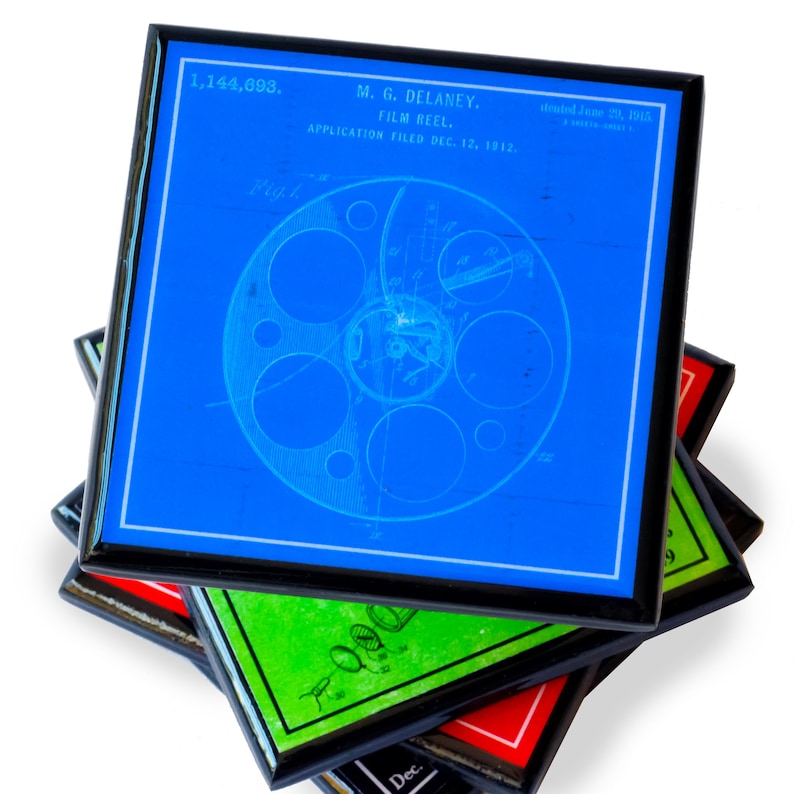 May include: A stack of four coasters in blue, green, red and black with a vintage blueprint design of a film reel. The top coaster has the text "1,144,693. M.G. DELANEY. FILM REEL. APPLICATION FILED DEC. 12, 1912.  Patented June 20, 1915."