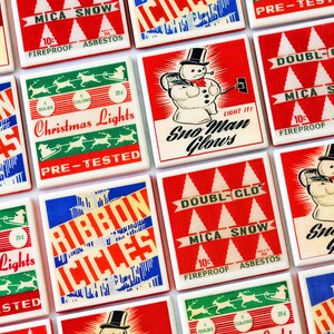 May include: A collection of vintage Christmas light boxes with red, white, and blue designs. The boxes feature images of snowmen, reindeer, and Christmas trees. The text on the boxes includes "MICA SNOW", "Christmas Lights", "Snow Man Glows", "Double-Glo", and "Ribbon Aciles".