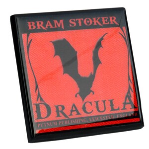 May include: Square black magnet featuring the title "DRACULA" and the author "BRAM STOKER" in white and gray text. A black bat silhouette is centered on a red background. The publisher's name and location are at the bottom.