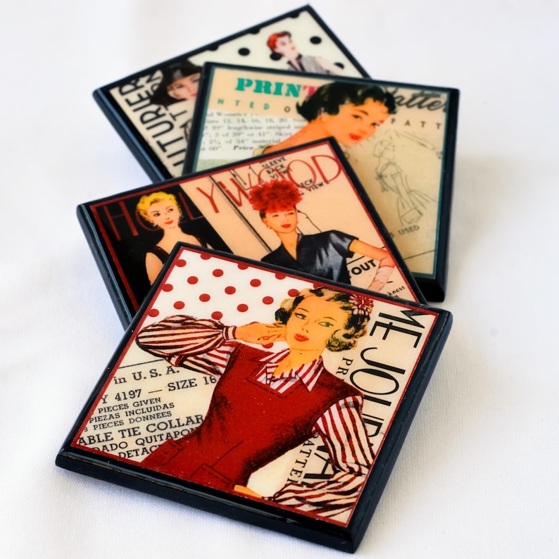 May include: Set of four square coasters featuring vintage magazine covers with images of women in red, white, and black. The coasters have black frames and are stacked on top of each other.