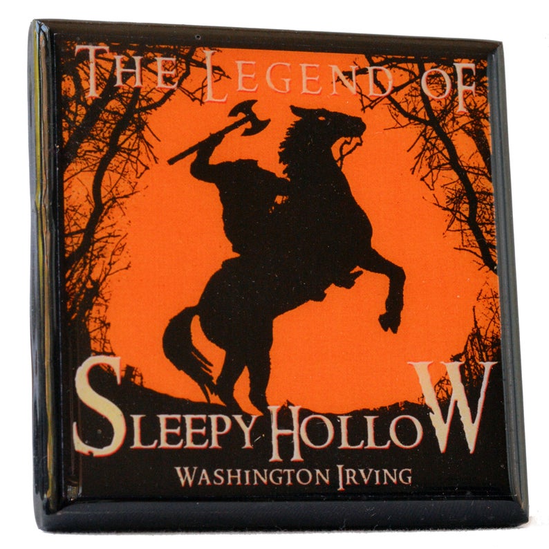 May include: Square magnet featuring a black silhouette of the Headless Horseman on horseback, holding an axe, against an orange background. The text "The Legend of Sleepy Hollow" and "Washington Irving" are displayed in white and gold.