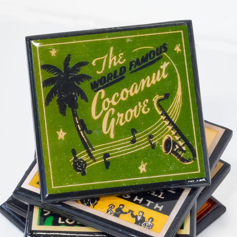 May include: A stack of four green and black coasters with a black border. The top coaster features a palm tree, musical notes, a saxophone, and the text "The World Famous Coconut Grove".