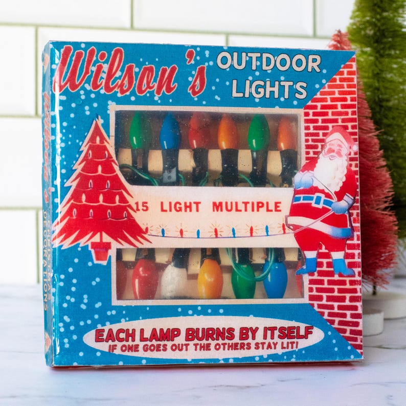 May include: Vintage box of Wilson's Outdoor Lights with a Christmas theme. The blue box features a red Christmas tree and a Santa Claus illustration. The box contains a string of 15 multi-colored light bulbs.