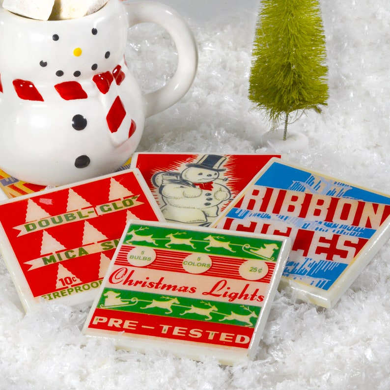 May include: Four vintage Christmas-themed coasters with red, white, blue, and green colors. The coasters feature images of a snowman, reindeer, and Christmas lights. The text on the coasters reads "Double-Glo", "Mica Snow", "Ribbon Isles", and "Christmas Lights".