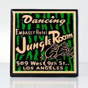 May include: A black and green sign with white lettering advertising the "Dancing Jungle Room" at the Embassy Hotel. The sign also includes the address "509 West 9th St., Los Angeles".