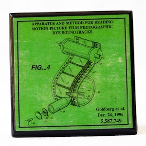 May include: A green patent drawing of a film projector with the text "APPARATUS AND METHOD FOR READING MOTION PICTURE FILM PHOTOGRAPHIC DYE SOUNDTRACKS" and "FIG._4" and "Goldberg et al. Dec. 24, 1996 5,587,749".