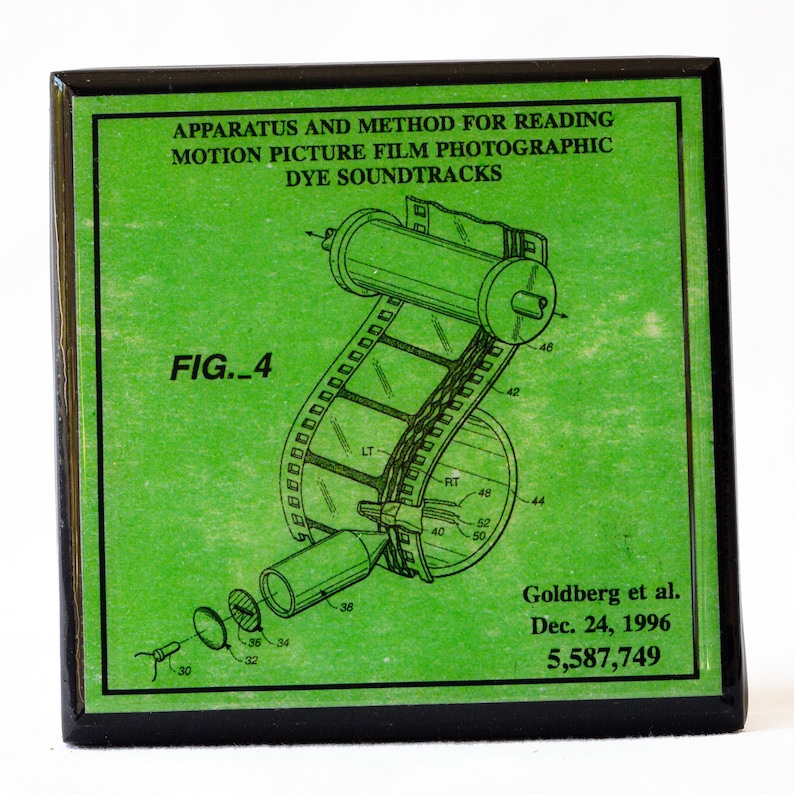May include: A green patent drawing of a film projector with the text "APPARATUS AND METHOD FOR READING MOTION PICTURE FILM PHOTOGRAPHIC DYE SOUNDTRACKS" and "FIG._4" and "Goldberg et al. Dec. 24, 1996 5,587,749".