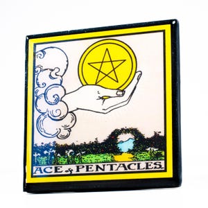 May include: Square tarot card featuring the Ace of Pentacles. The image shows a hand holding a yellow coin with a star, set against a landscape. The card has a yellow border and the words "ACE of PENTACLES" at the bottom.