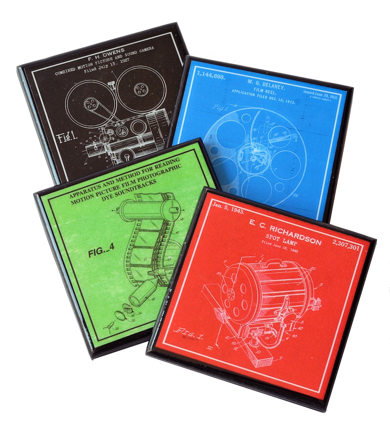 May include: Four framed vintage patent prints for film equipment. The prints are in black, blue, green, and red. The prints feature illustrations of film reels, cameras, and a spot lamp. The text on the prints includes the patent numbers, inventors' names, and dates.