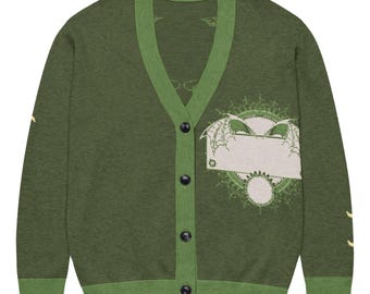 May include: Olive green cardigan with a V-neck and button closure. The sweater features a contrasting green trim and a graphic on the front with a blank space. The sleeves have a small design. A stylish and unique piece.