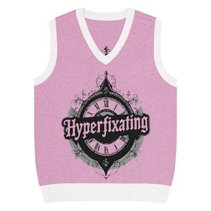 May include: Pale pink sleeveless sweater with a white V-neck and edging. The front displays a black clock graphic with the text "Hyperfixating". A casual garment.